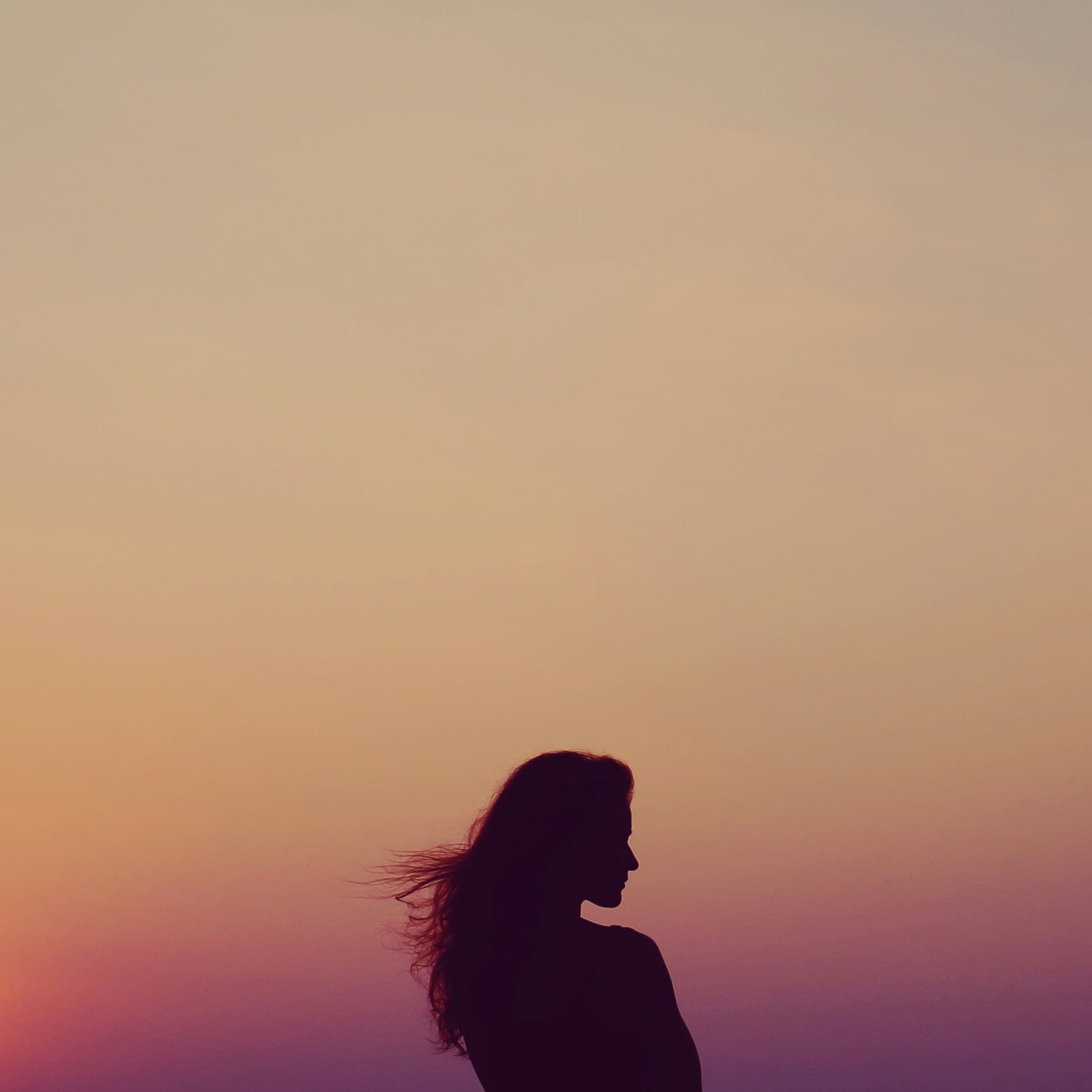 Silueta de mujer mirando hacia el atardecer