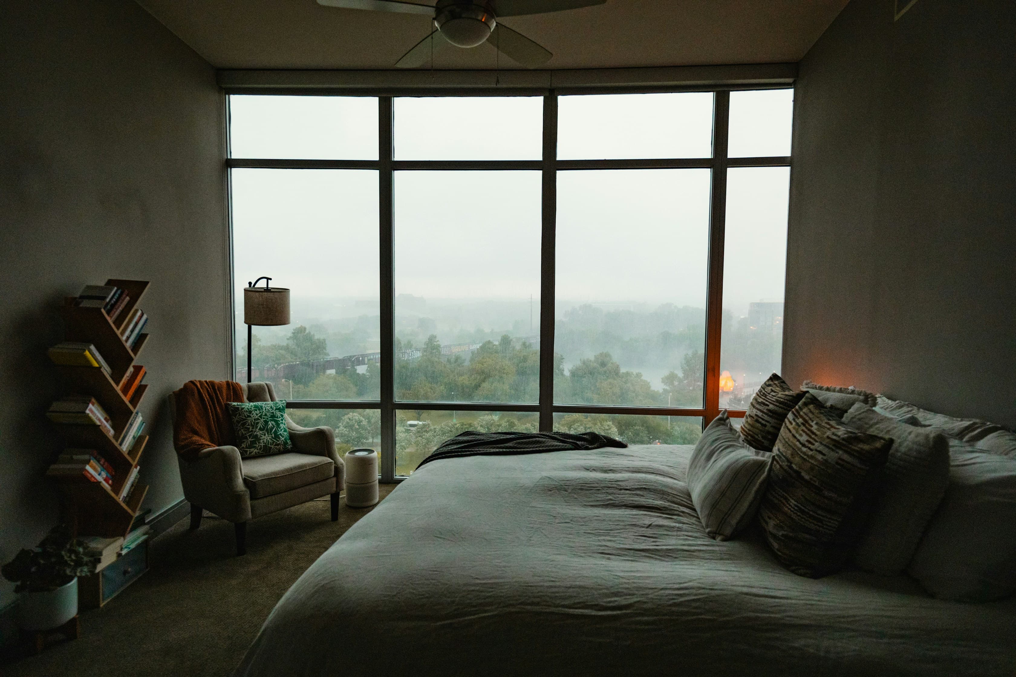 Mujer sentada en la cama mirando hacia la ventana