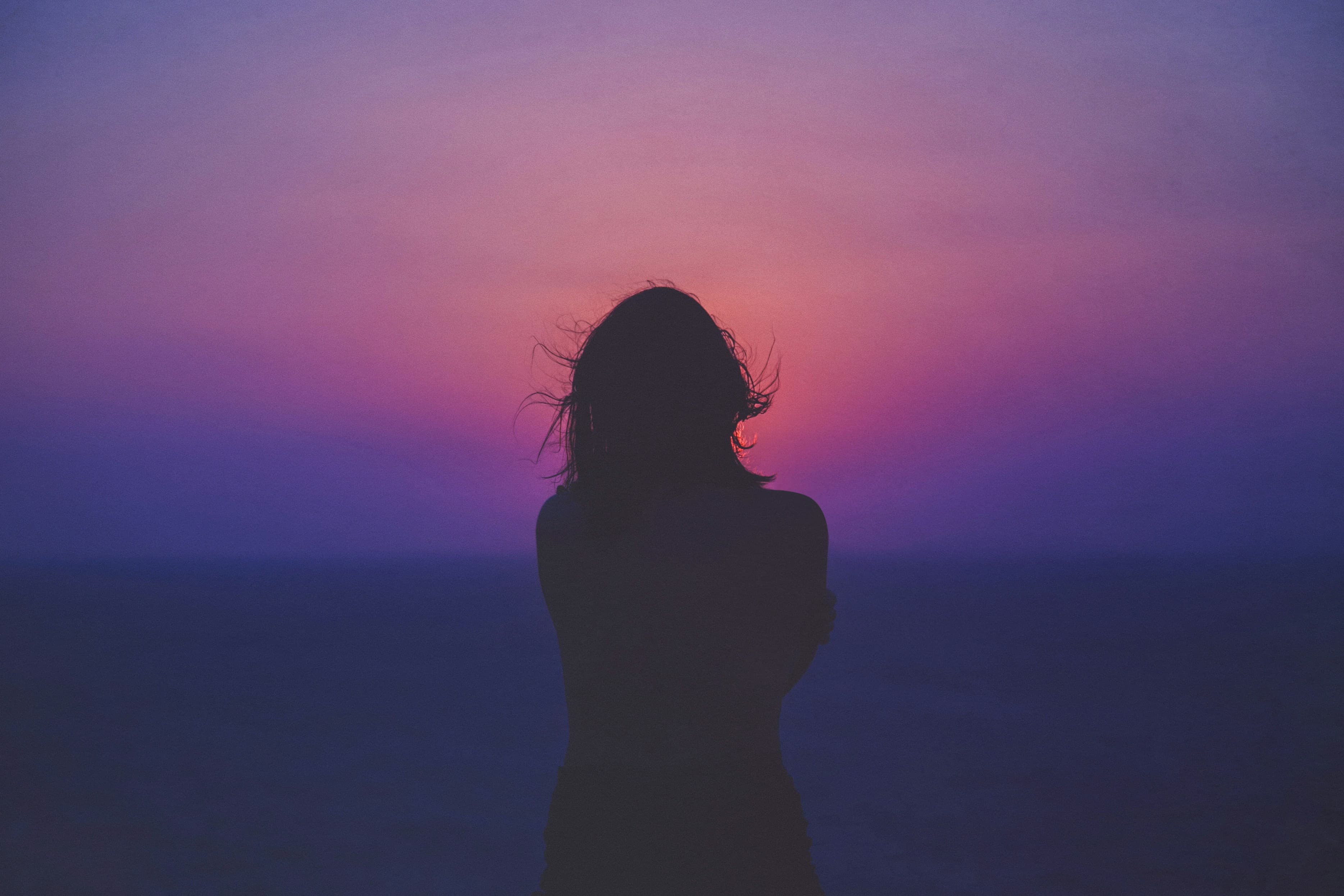 Silueta de mujer recortada contra un cielo de atardecer